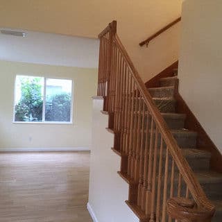 Interior view of a home featuring a staircase, light-colored walls, and a large window.