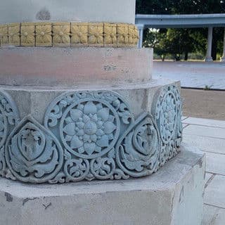 Detailed decorative carvings on a stone base with floral motifs and golden accents.