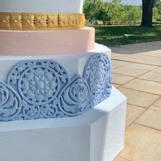 Decorative pedestal with intricate blue carvings and gold accent, set outdoors.